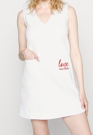 Weißes ärmelloses Kleid mit V-Ausschnitt, vorne links eine Tasche mit roter "love"-Stickerei. Weicher Stoff und lockere Passform.