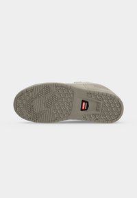 Semelle d'une chaussure gris clair avec une semelle à motif et une petite étiquette rouge et noire indiquant "Globe Nitrol."