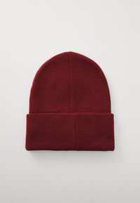 Bordeaux gebreide beanie muts, gemaakt van zacht materiaal, heeft een omgeslagen rand en een ronde bovenkant, geschikt voor koud weer.