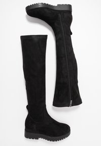 Bottes noires au-dessus du genou en matière semblable au daim, dotées d'une fermeture éclair latérale, d'un bout arrondi et d'une semelle extérieure en caoutchouc texturé.