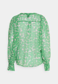 Blouse verte avec motif abstrait blanc, manches longues bouffantes, poignets boutonnés et empiècement dos avec pli.