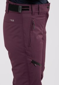 Bordeauxrode outdoorbroeken met een gladde textuur, voorzien van ritszakken en een zwarte verstelbare tailleband voor een veilige pasvorm.
