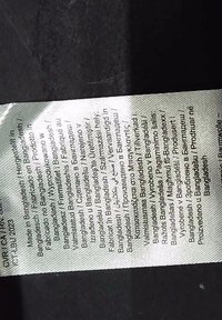 Étiquette de vêtement indiquant les détails de fabrication en plusieurs langues, précisant que le produit est fabriqué au Bangladesh.