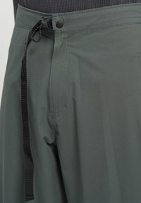 Γκρι αθλητικές παντελόνες φτιαγμένες από υφασμάτινη ύφασμα με ρυθμιζόμενη μέση και κουμπί κλεισίματος, με τσέπες στο πλάι και σχέδιο χαλαρής εφαρμογής.