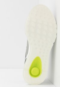 Suola della scarpa con una base in gomma bianca testurizzata, con un evidente inserto verde e modelli circolari per una migliore aderenza.