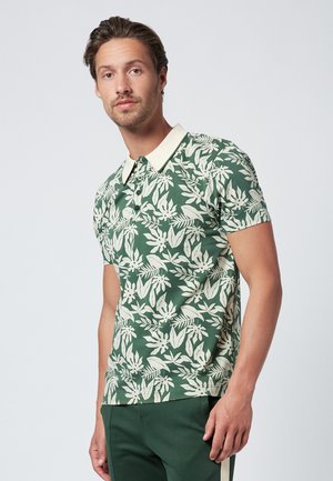 Grøn polo t-shirt med et hvidt blomstermønster, korte ærmer og en kontrasterende lysefarvet krave, lavet af blødt stof.