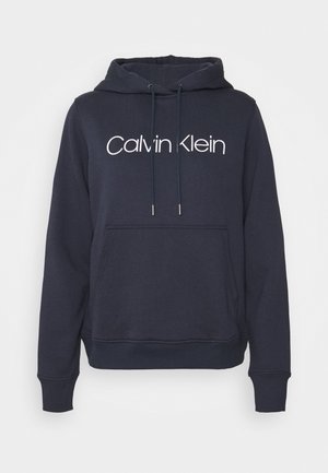 Navy blue hoodie with front kangaroo pocket, adjustable drawstring hood, ribbed cuffs, and white "Calvin Klein" logo across the chest.