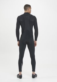 Schwarzer sportlicher Neoprenanzug mit langen Ärmeln, figurbetontem Design, strukturiertem Obermaterial, glattem unteren Bereich und "ENDURANCE" auf dem Bein gedruckt.