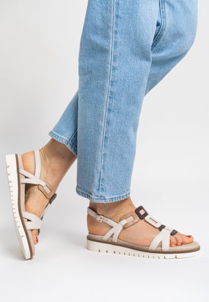 Leichte Sandalen mit weißen Lederriemen und braunen Akzenten, ausgestattet mit einer dicken weißen Sohle mit strukturiertem Muster für besseren Halt.