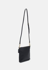Černá kožená krosbodová taška s hladkým povrchem, obdélníkovým tvarem, nastavitelným popruhem, zlatými kovovými detaily a zipovým uzávěrem.