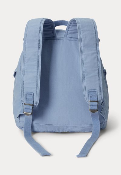 Mochila ligera de lona azul clara vista desde atrás, con correas acolchadas ajustables para los hombros y un asa superior para llevar.
