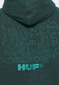 Dark green hoodie featuring a large turquoise embroidery design with abstract graphics and text, "HUF," on the back.