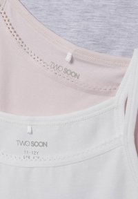 Trois débardeurs en lavande, blanc et rose. Tissu en coton lisse avec des bordures en dentelle le long de l'encolure. Les étiquettes indiquent la marque "TWO SOON" et les tailles.