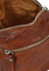 Braune Ledertasche mit silbernem Reißverschluss, ausgestattet mit einer strukturierten Oberfläche und einem geräumigen, beige-farbenen Innenfutter aus Stoff. Sichtbares Detail mit Reißverschlussfach.