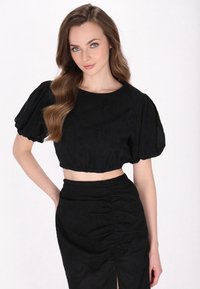 Mustapaitainen cropped-top, jossa on puffihihat, tekstuuriainen kangas ja kerätty helma, yhdistettynä vastaavaan hameeseen, jossa on sivureikä ja hienovarainen rypytys.