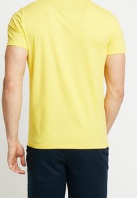 Gul bomull t-shirt med korta ärmar, enkel design, standard passform och rundad halsringning. Slät textur, inga synliga grafik eller mönster.