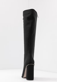 Knee-high černá syntetická bota s hladkým povrchem, zúženým designem a blokovým podpatkem. Obsahuje boční zip pro snadné obouvání.