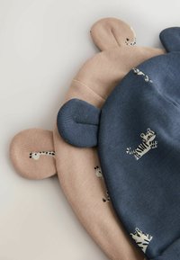 Divas bērnu cepures ar ausīm, viena gaiši bēša ar žirafes rakstu, otra tumši zila ar zebras rakstu. Mīksta adīta auduma tekstūra.