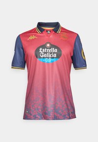 Sarkans un tumši zils futbola krekls ar apkakli, ar gradienta dizainu, logotipiem un lielu melnu sponsora emblēmu uz priekšpuses.