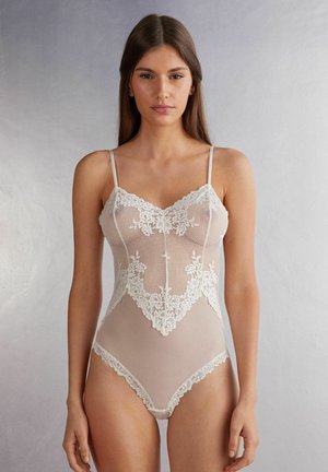 Spetsbodysuit i elfenbensfärg med vågig halsringning och blommönster, med tunna band och ett genomskinligt meshmaterial.