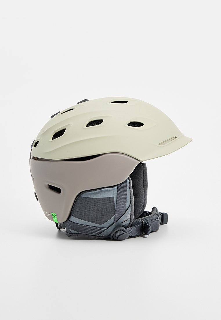 Kask narciarski w kolorze off-white i szarym. Posiada otwory wentylacyjne, wyściełane wnętrze oraz regulowane paski dla zapewnienia bezpiecznego dopasowania.