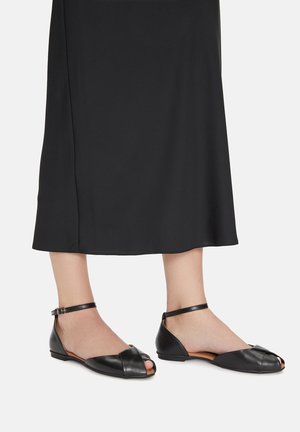 Fekete bőrcipők kivágott dizájnnal, nyitott orral és bokapánttal. Simító textúrával és minimalista formával rendelkeznek, alkalmasak hétköznapi viseletre.