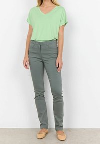 Lichtgroen V-hals t-shirt met korte mouwen, gecombineerd met een fitted grijze broek. Beige ballerina's maken de outfit af. Eenvoudig en casual ontwerp.