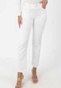 Witte denim jeans met een rechte pijp, voorzien van zakken en een knoopsluiting. Glad van textuur en met strakke lijnen. Gecombineerd met sandalen met een transparante hak.