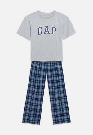 T-shirt gris clair à manches courtes avec le texte GAP, associé à un pantalon de pyjama à carreaux bleu et blanc, posé à plat sur un fond blanc.