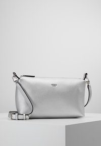 Zilverkleurige lederen crossbody tas met een afneembare schouderband, voorzien van een ritssluiting en minimale branding aan de voorkant.
