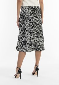 Midi-nederdel i leopardprint med en flydende silhuet, sort og beige farveskema, der har en glat tekstur og en kant, der falder under knæet.