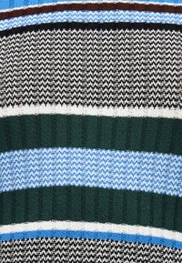 Κοντινή λήψη πλεκτού υφάσματος με οριζόντιες ρίγες σε μαύρο, λευκό, ανοιχτό μπλε, σκουροπράσινο και καφέ, με ποικίλα υφασμάτινα σχέδια.