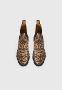 Ankelsko med leopardmønster som har et teksturert ytre i brunt og svart, elastiske sideinnsatser og en solid svart såle.