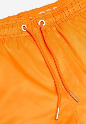 Helderskleurige oranje zwemshorts met een elastische tailleband, voorzien van witte oogjes en een trekkoord met metalen eindstukken. Glad, lichtgewicht materiaal.