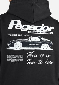 Black hoodie featuring a vintage car graphic and white text. Design includes "Pegador," "Everyday Ambition," and additional print details.