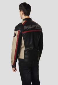 Black and beige leather motorcycle jacket featuring red accents and "RIDERS" logo on the back; textured panels and fitted design.