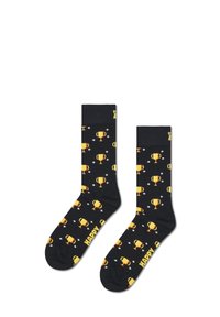 Chaussettes noires avec un motif répété de trophées jaunes et d'étoiles, comportant le mot "HAPPY" en blanc sur la cheville. Texture de tissu lisse.