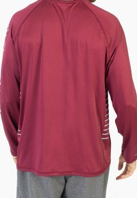 Bordowa sportowa koszulka z długim rękawem o gładkiej strukturze z szarymi paskami po bokach, z okrągłym dekoltem i prostym wykończeniem na dole.