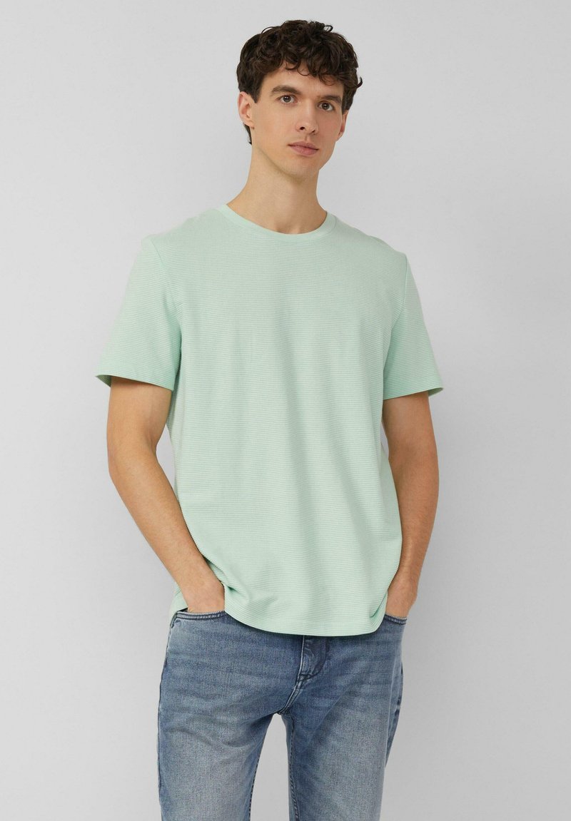 Heleroheline lühikeste varrukatega t-särk ümarate kaelustega ja peene tekstuuriga, sobitatud siniste teksadega. Lõige on lõdvestunud, sobides vabaaja kandmiseks.