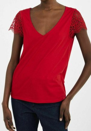 Haut rouge à manches courtes avec un col en V et des accents en dentelle sur les manches. Confectionné dans un tissu lisse avec une silhouette ajustée.