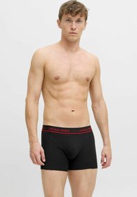 Zwarte boxershorts met rode tailleband, met het merk "JACK & JONES" in het wit gedrukt. Glad, rekbaar materiaal.
