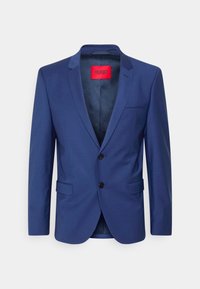 Navyblauwe colbert met scherpe kleppen, twee knopen en klepzakken. Heeft een rood merklabel aan de binnenkant, met een gladde textuur overal.