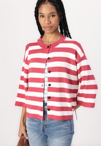 Rood- en witgestreepte cardigan met een ronde hals, knopen aan de voorkant en korte mouwen, gecombineerd met een blauwgestreept shirt en denim jeans.