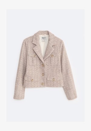 Krótka kurtka z mieszanki wełny w jasnym beżu z wzorem w jodełkę. Posiada podwójne zapięcie, dwie kieszenie z przodu oraz złote guziki.
