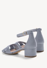 Sandales à bride cheville en daim bleu clair avec détails découpés sur les côtés et petits talons carrés, dotées de boucles dorées.