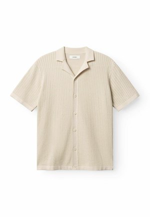 Beige short-sleeve shirt with a textured, ribbed pattern, featuring a collar and five buttons down the front. Smooth fabric finish.