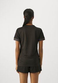 Black t-shirt with short sleeves, round neck, textured fabric, contrasting dark grey trim on sleeves, paired with black shorts.