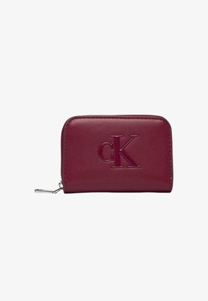 Portefeuille en cuir bordeaux Calvin Klein avec logo embossé, fermeture éclair, texture lisse, bords arrondis et ferrures argentées.