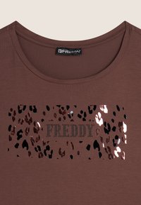 T-shirt marron avec un col rond arborant un motif léopard en accents métalliques et le mot "FREDDY" en strass.