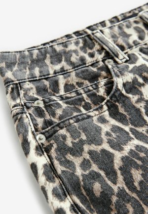 Dierenprint jeans met een beige en zwart patroon, gemaakt van denim met een gestructureerde afwerking, voorzien van zilveren hardware en stiksels.